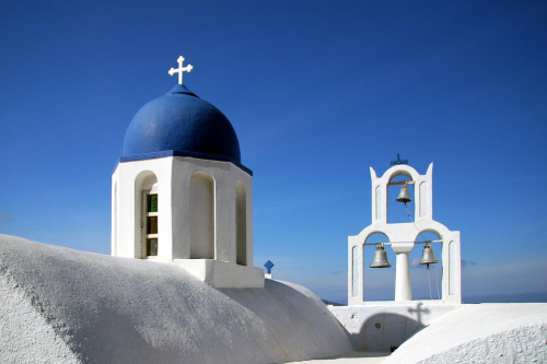 An aerial photo of a blue-domed church in Santorini.