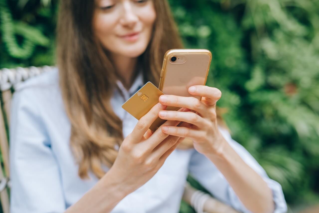 woman holidng phone and credit card and smiling
