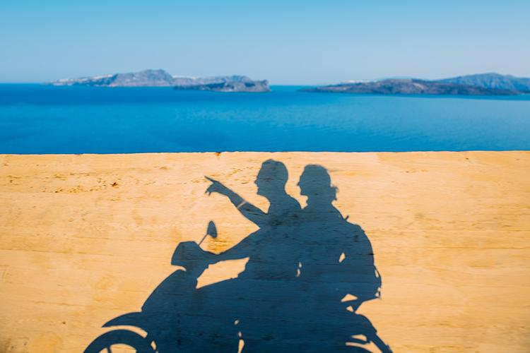 SA couple riding motor bike along side the beautiful coast of Santorini.