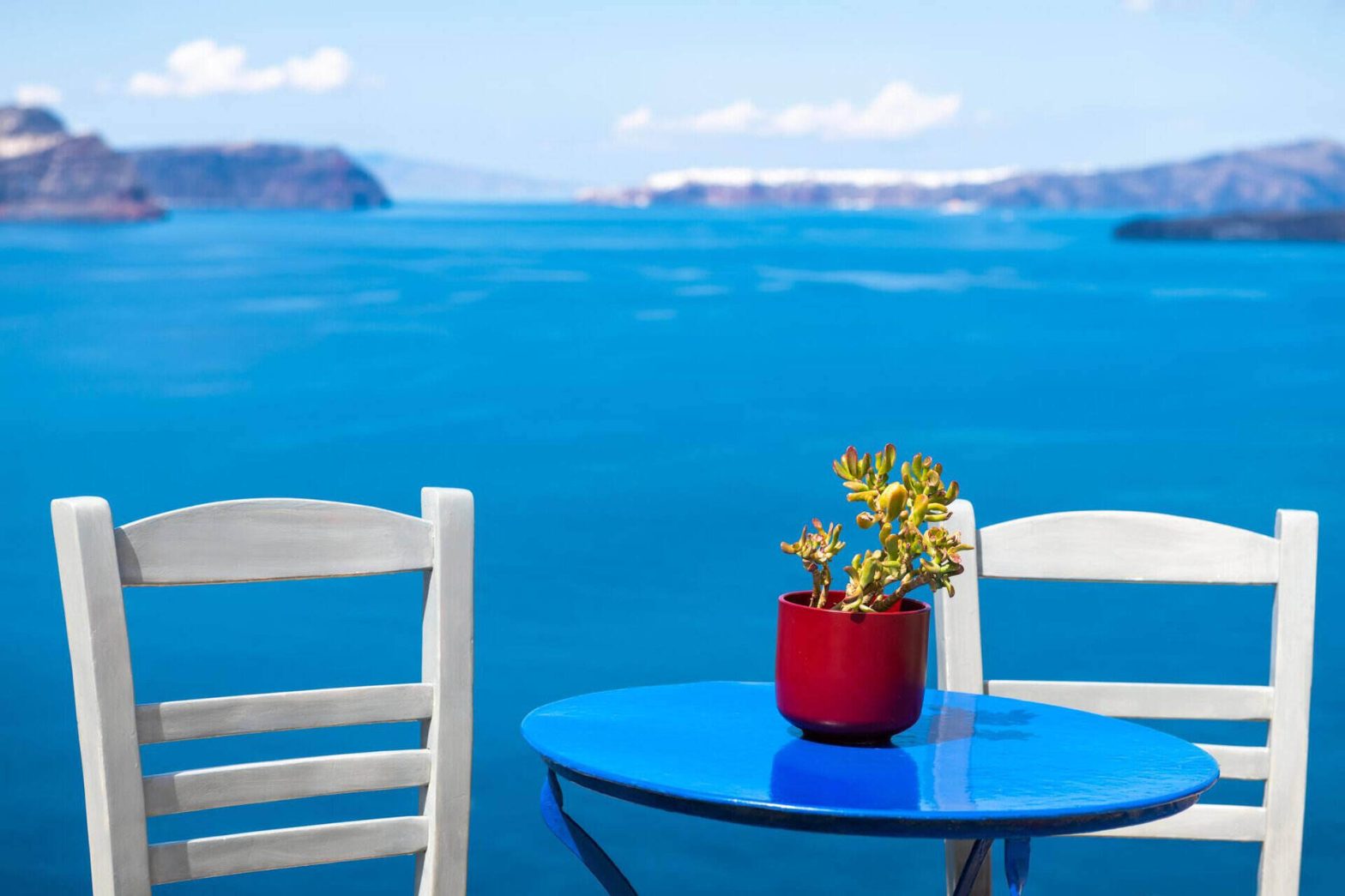Santorini isola greca turistica due sedie bianche con tavolo blu sulla terrazza con vista mare
