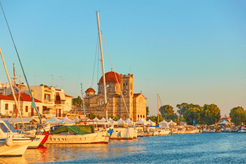 ψαροβαρκες αραγμενες στο λιμανι της Αιγινας ενα απογευμα καλοκαιριου καθως το ηλιοβασιλεμα εχει δημιουργησει πορτοκαλι αποχρωσεις στα λευκα κτιρια με κοκκινες σκεπες