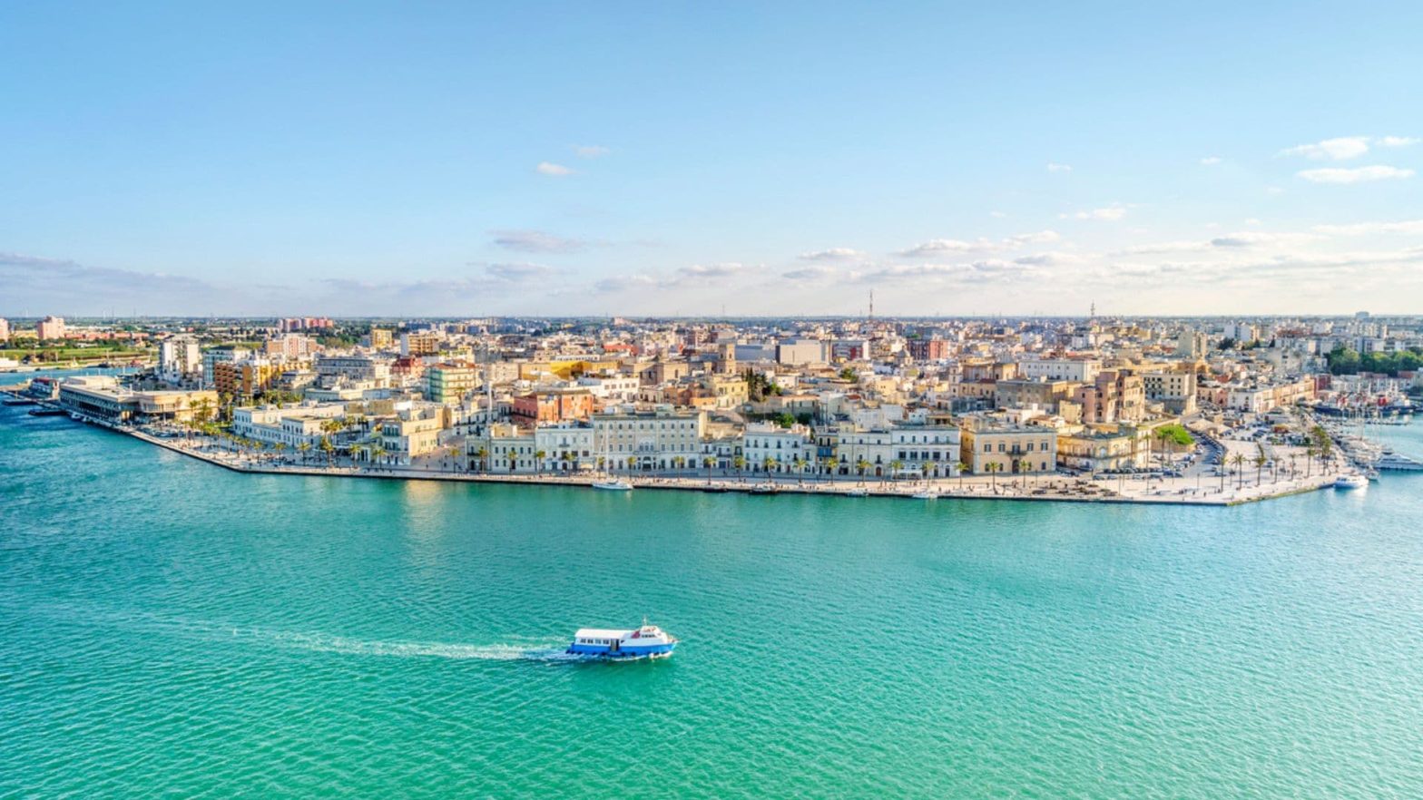 Πανοραμική φωτογραφία του Μπρίντιζι, Ιταλίας με ένα πολυσύχναστο λιμάνι, γαλαζοπράσινα νερά και ένα μείγμα αρχαίας και σύγχρονης αρχιτεκτονικής.