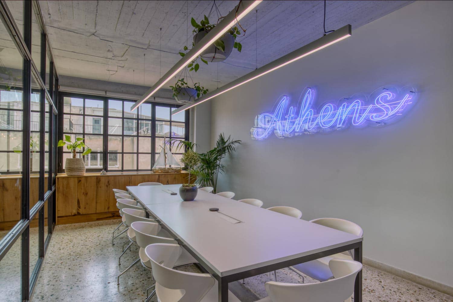 a meeting room with a large white table and white chairs around with a blue neon light on the wall.