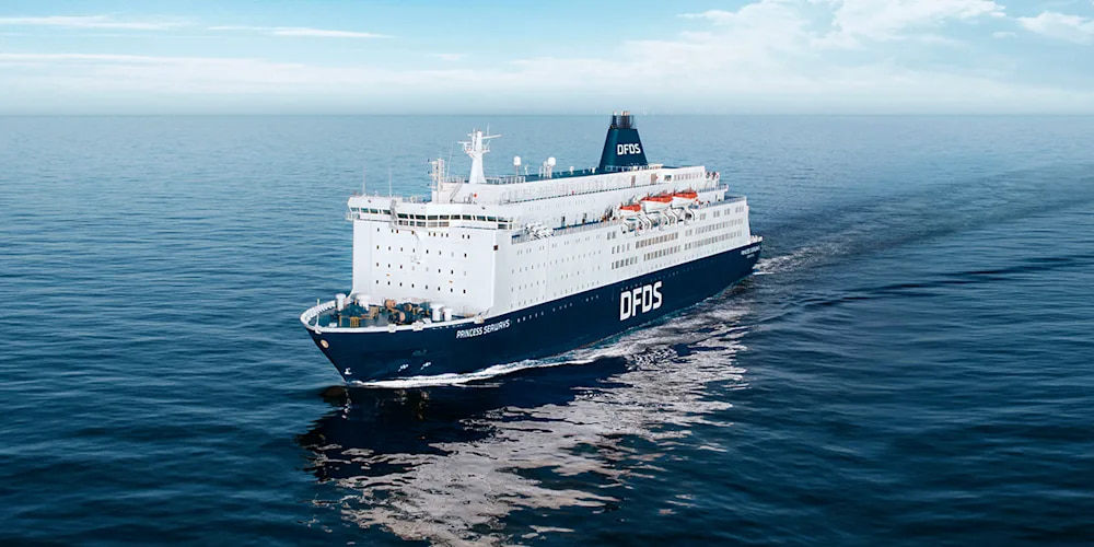 DFDS ferry sailing across the open sea under a clear blue sky. The ship, marked with the DFDS logo, offers a scenic and relaxing journey on the water.