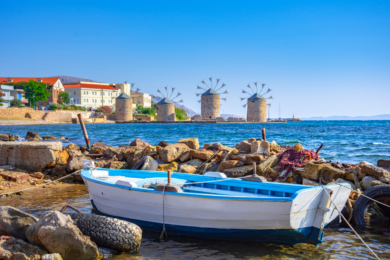 The four windmills of Chios island with a small boat on the front.