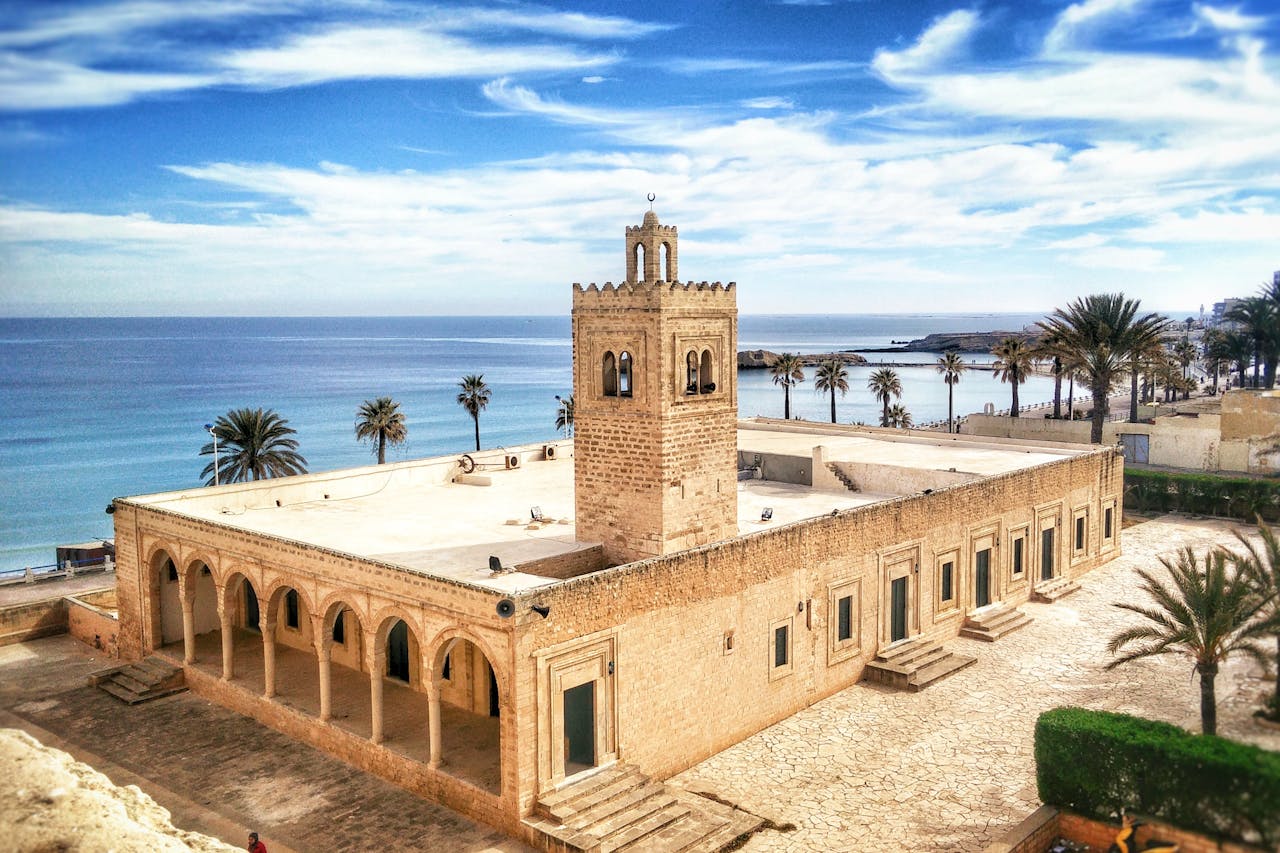 A beautiful Tunisian monument surrounded by palm trees and the sea.