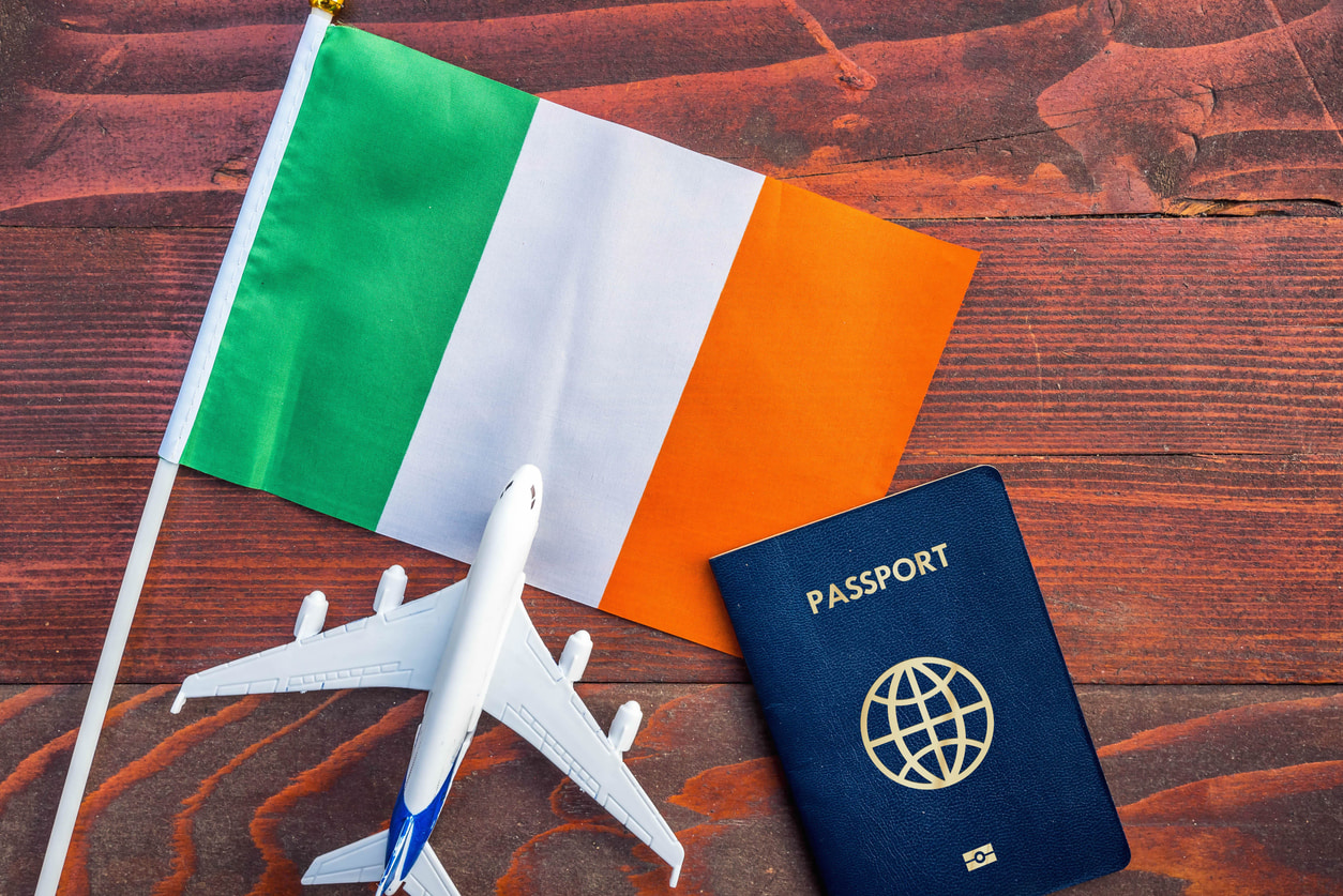 Un drapeau irlandais (vert, blanc et orange), une miniature d'avion et un passeport bleu.
