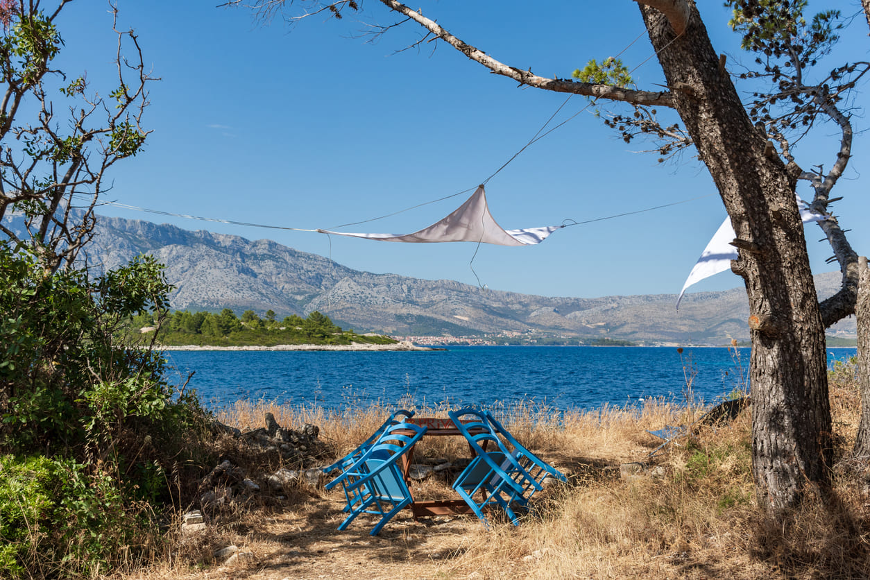 Dva plava stolca nahnuta na stol s pogledom na more i planine
