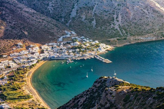 Vista aerea del porto di Kamares a Sifnos, circondato da montagne e bagnato da un mare calmo e cristallino.
