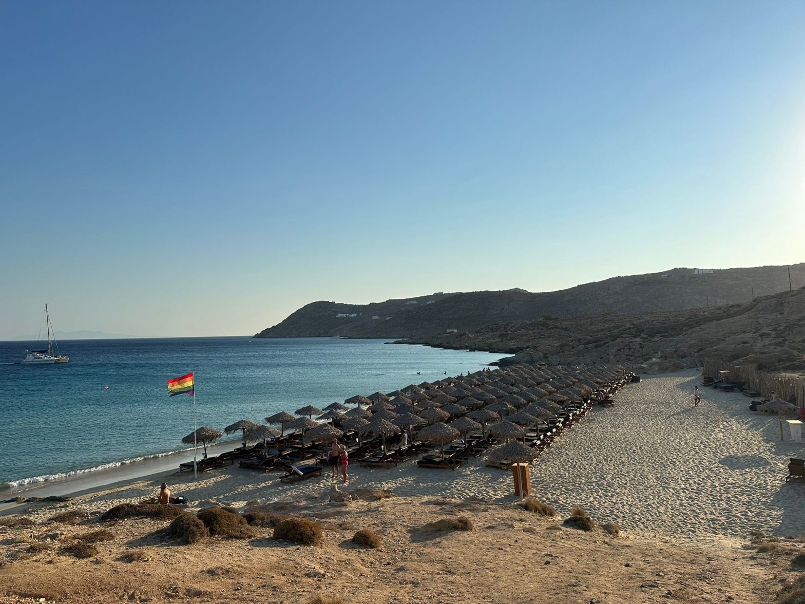 Plage Elia avec des chaises longues et un drapeau arc-en-ciel au vent
