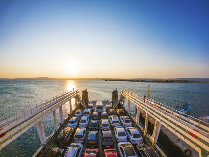 Traghetto al tramonto con auto imbarcate sul ponte, pronto a salpare