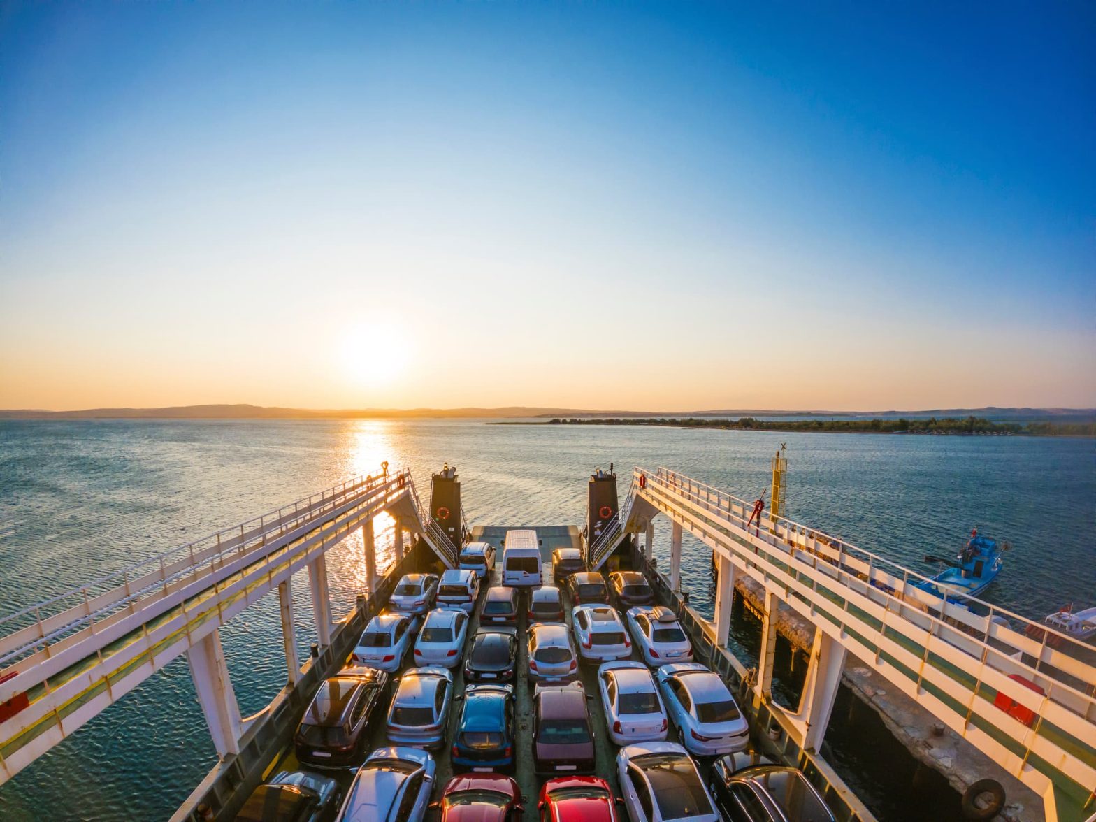 Traghetto al tramonto con auto imbarcate, in partenza dal porto verso le isole.