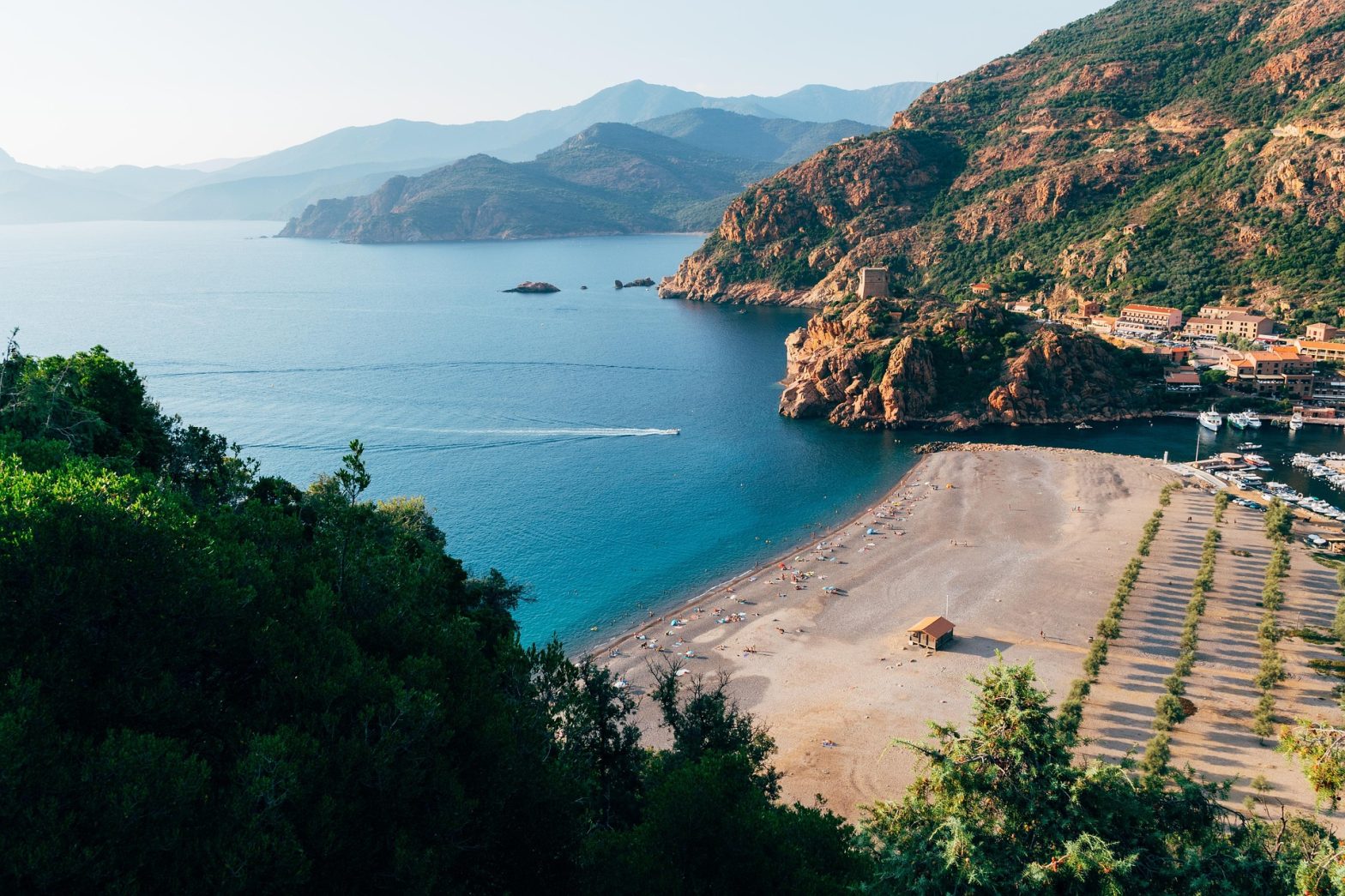 Panoramica sulla spiaggia di Porto, sulla costa occidentale della Corsica, circondata da montagne e scogliere rosse con acqua cristallina.