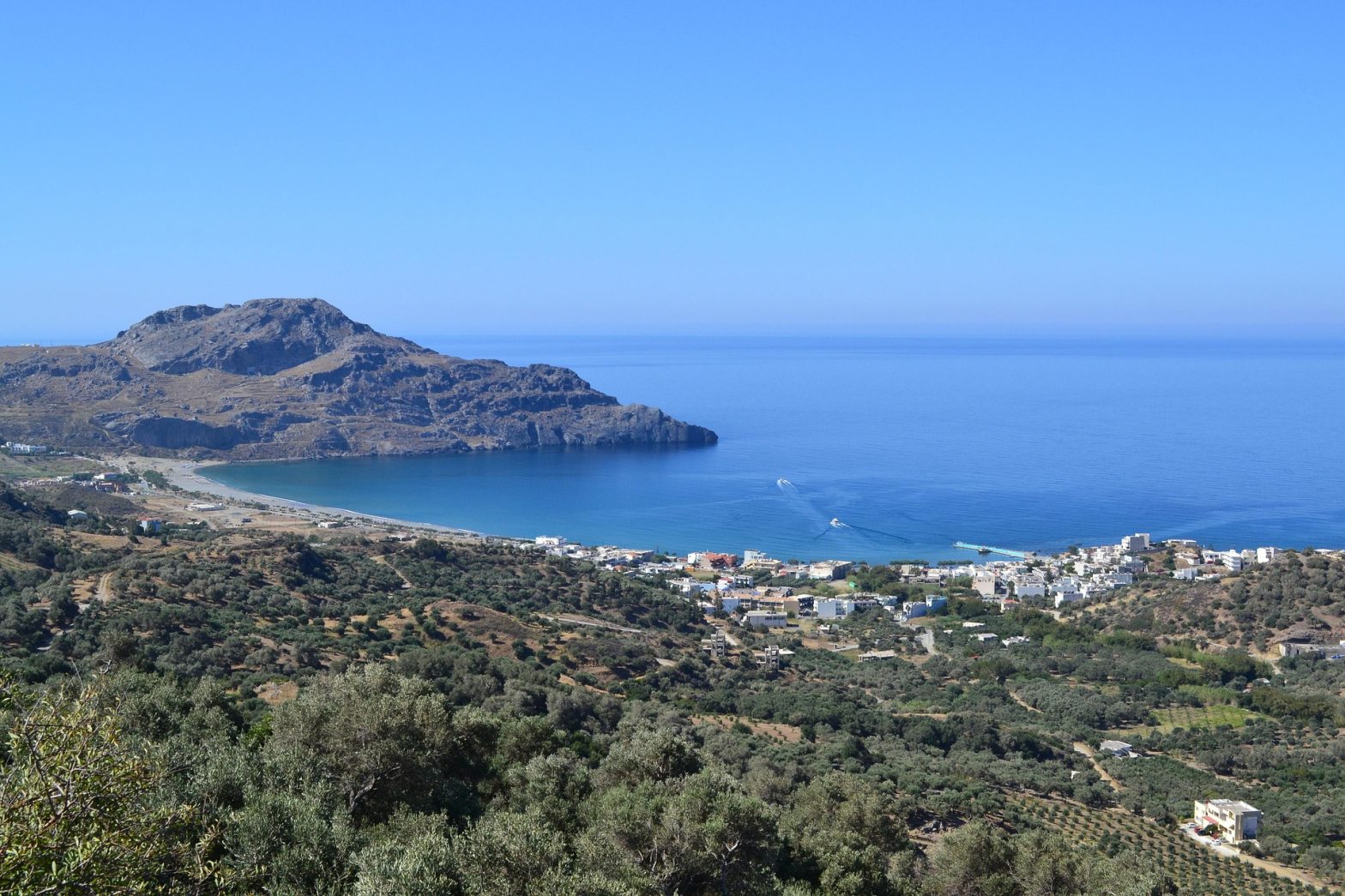 Veduta panoramica della costa di Creta con il villaggio di Plakias, il mare calmo e le colline circostanti ricoperte di vegetazione mediterranea.