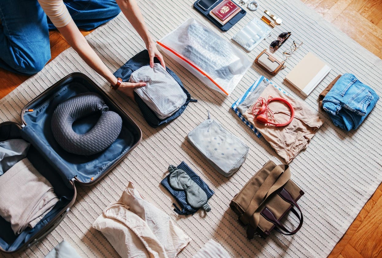 Putni jastuk, maska za oči, putovnice, i druge stvari uredno poredane i spremne za pakiranje.