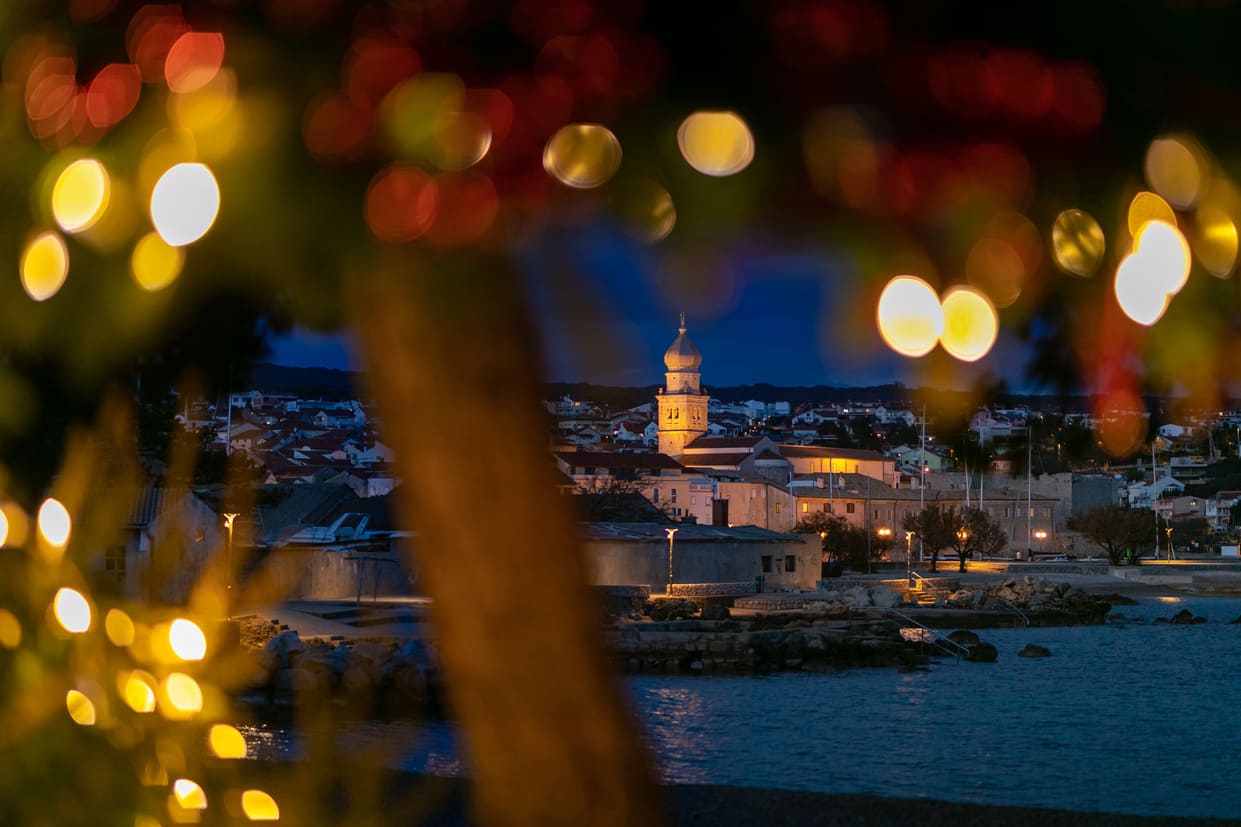 Pogled na Crkvu Svetog Kvirina u Gradu Krku na otoku Krku noću uokvirenu božićnim lampicama.