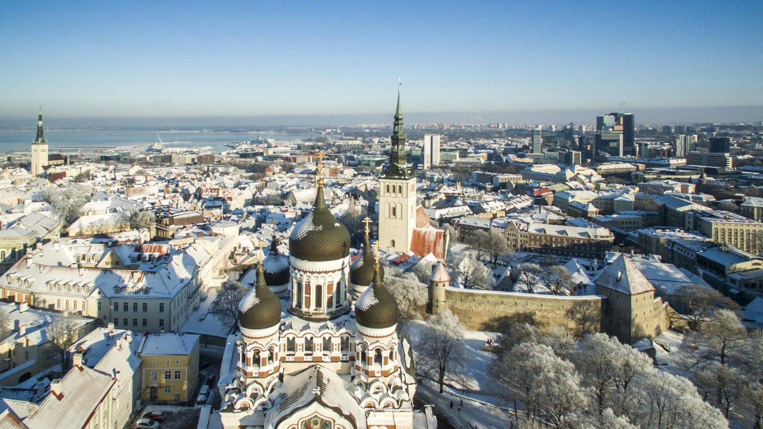 Veduta panoramica invernale di Tallinn, con la Cattedrale di Aleksandr Nevskij in primo piano e la città coperta di neve che si estende fino al porto sul Mar Baltico.