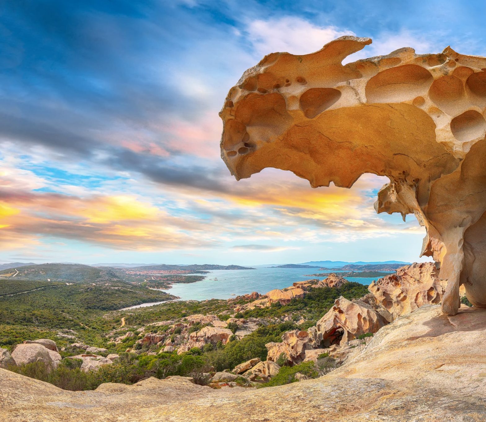 Une formation rocheuse étonnante comme un gruyère sur une falaise donnant sur un paysage magnifique en contrebas.